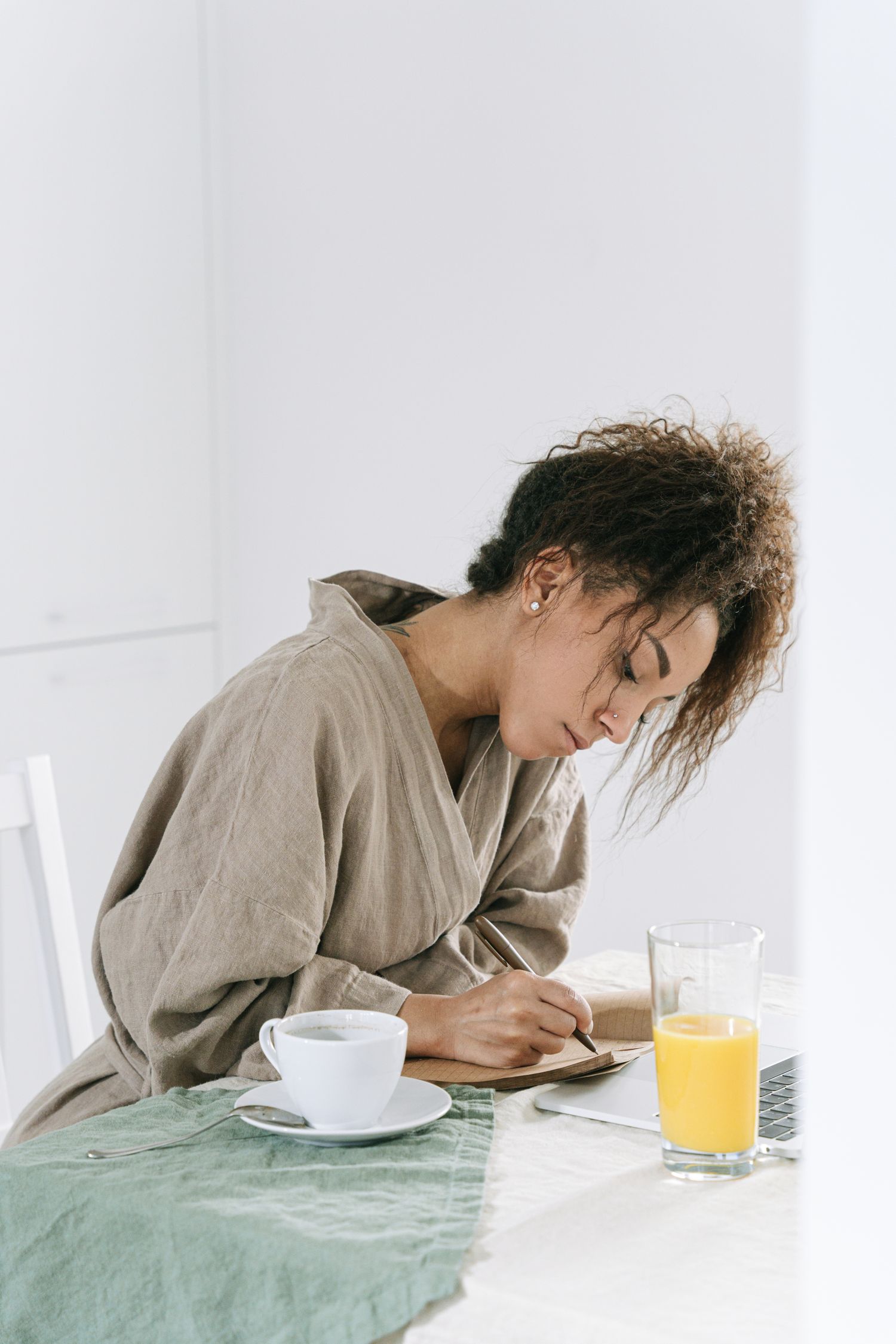 A woman writing in her journal at a breakfast table